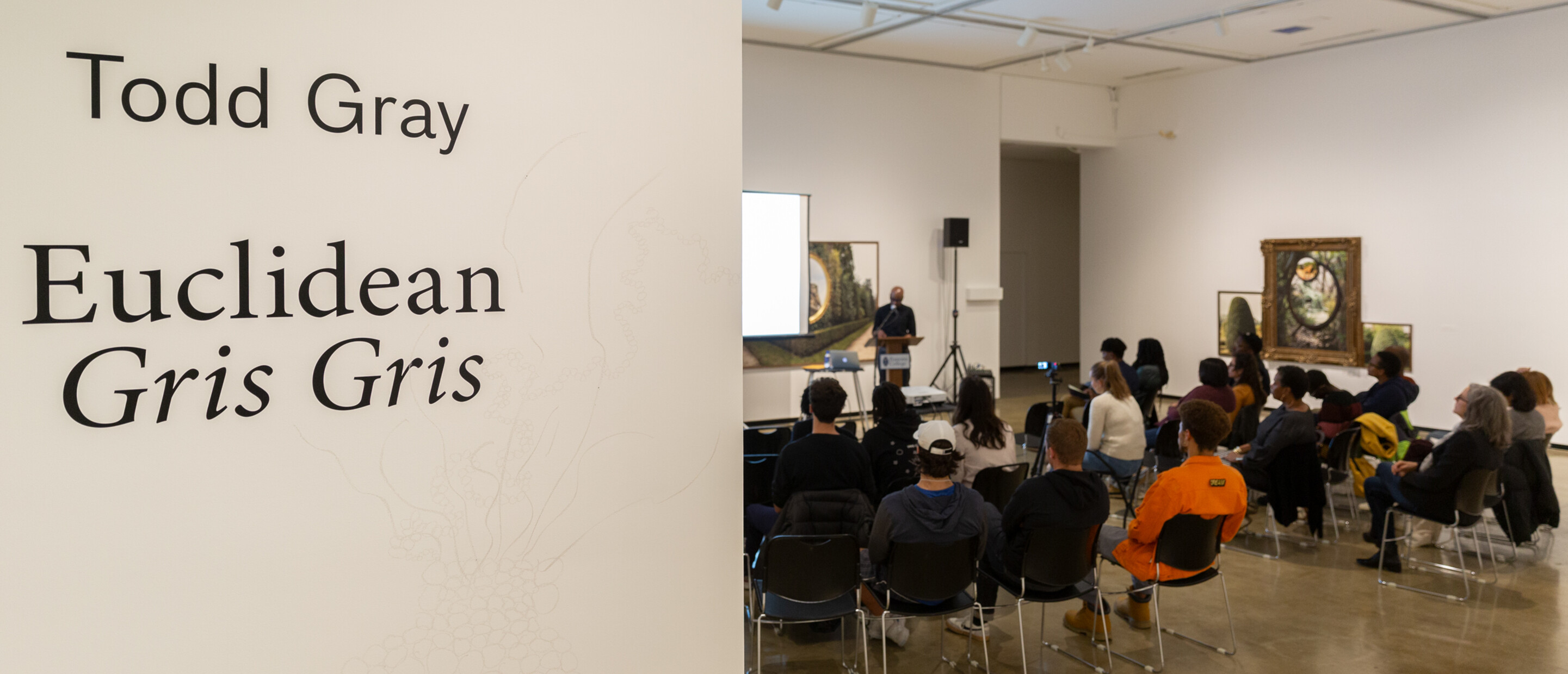 View into a gallery for a public lecture with audiences in seats with a speaker up front