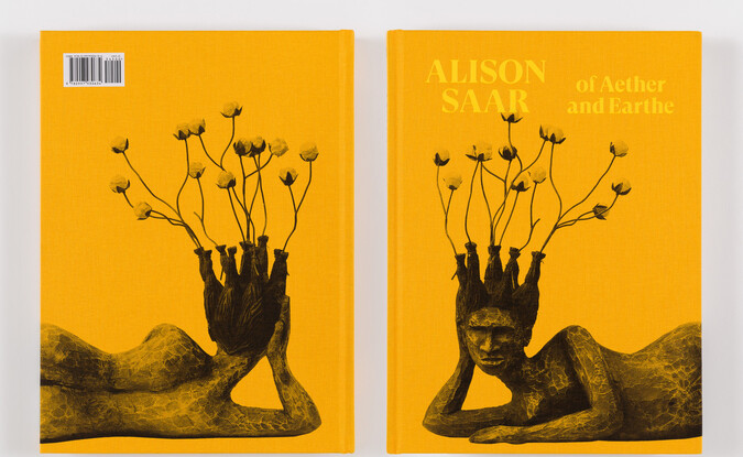 Photograph of both sides of a book titled Alison Saar: Of Aether and Earthe with image of sculpture front and back