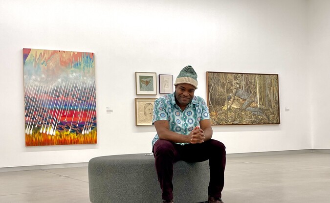 Person sitting in gallery with artworks installed in the background