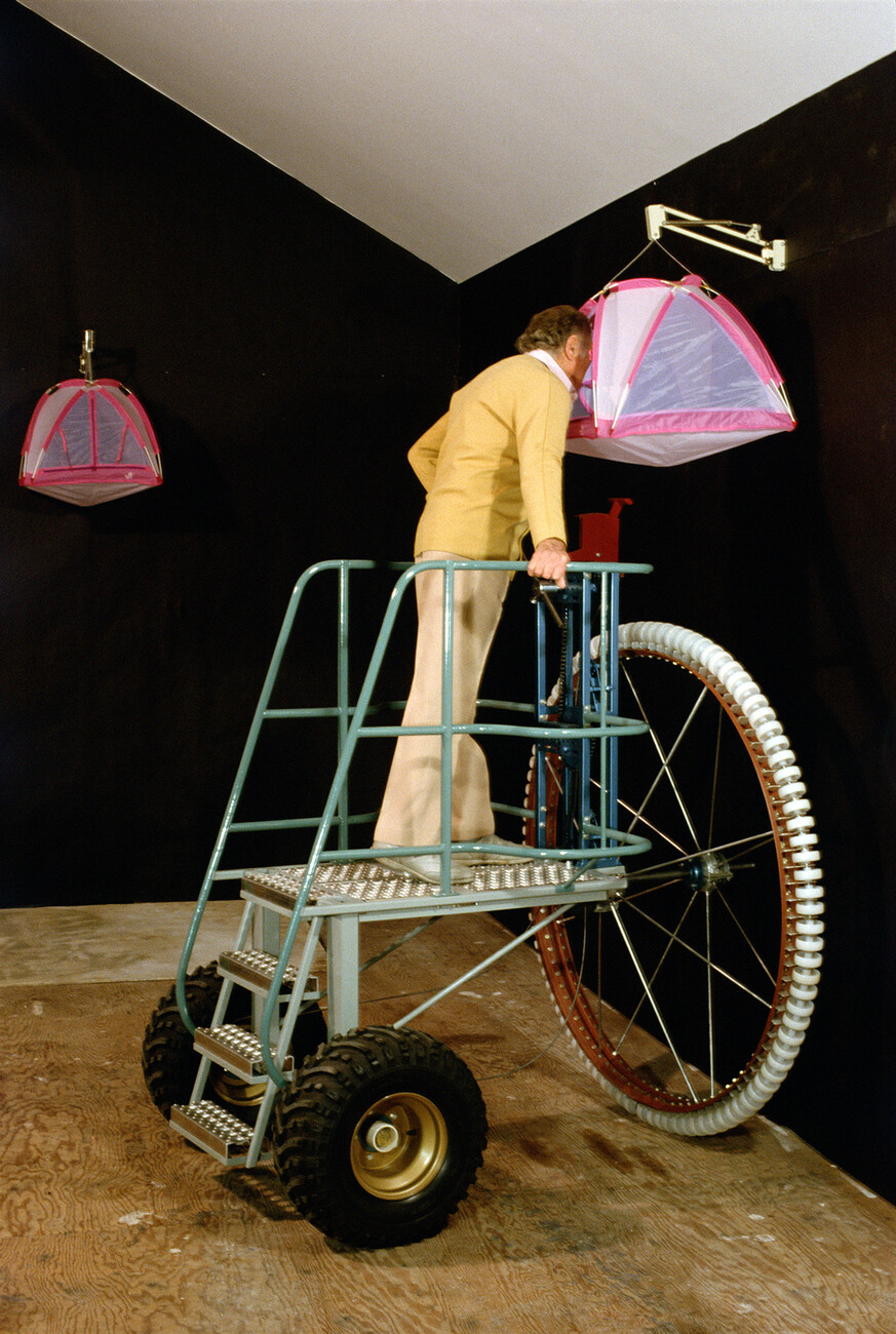 A person looking through a small tent mounted high using a cycle with stairs moving structure