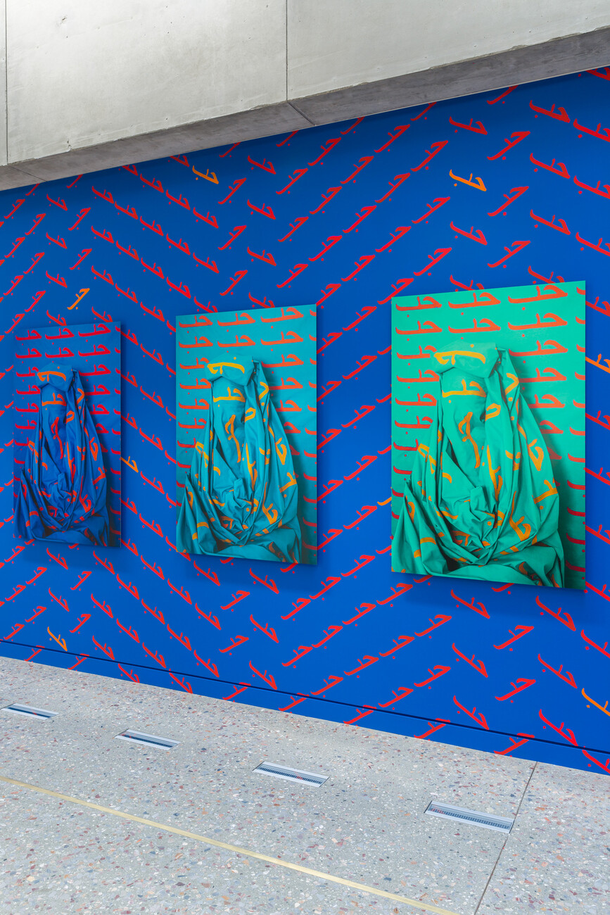 Close up of photographs again blue painted wall with the word LOVE/حب repeatedly