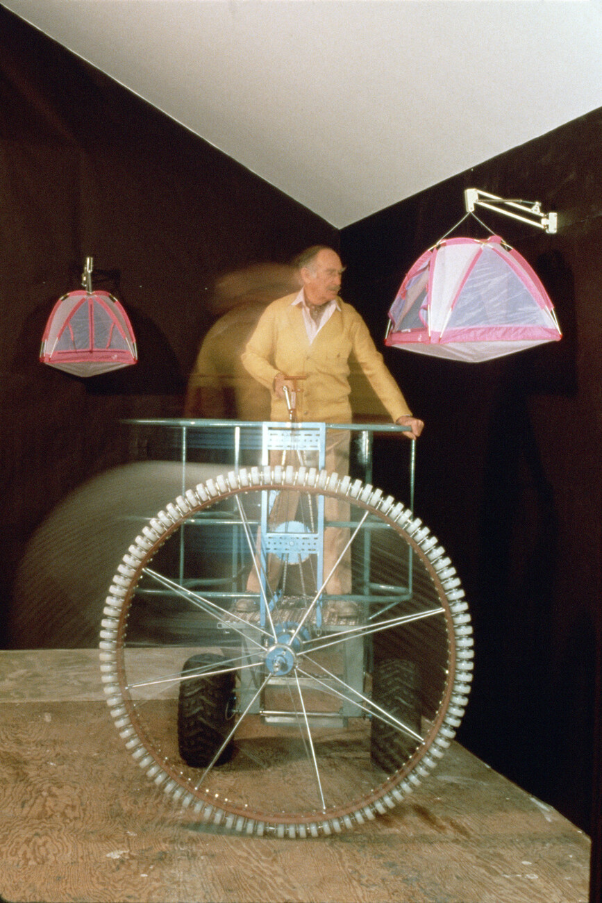 A person in motion on cycle like contraption maneuvering from tent container hanging on walls