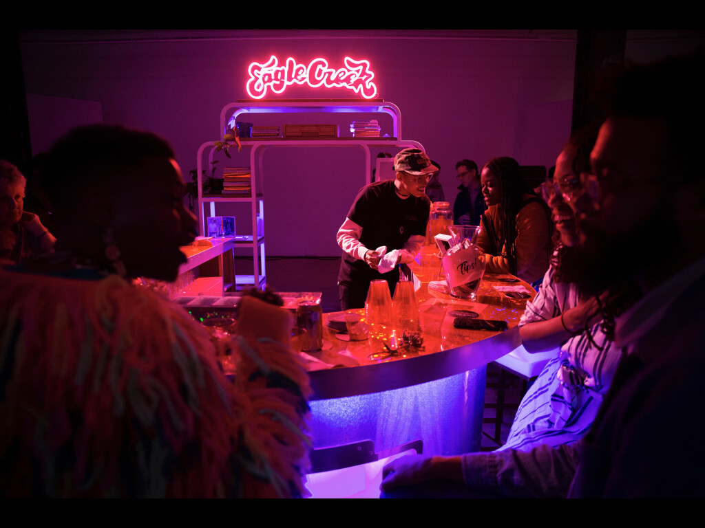 Neon lit bar space with Eagle Creek in neon signs with lots of people