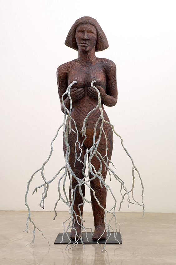 Sculpture of figure standing naked with white branch like pieces