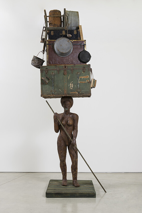 Large figure on raft holding stack of boxes or trunks above the head