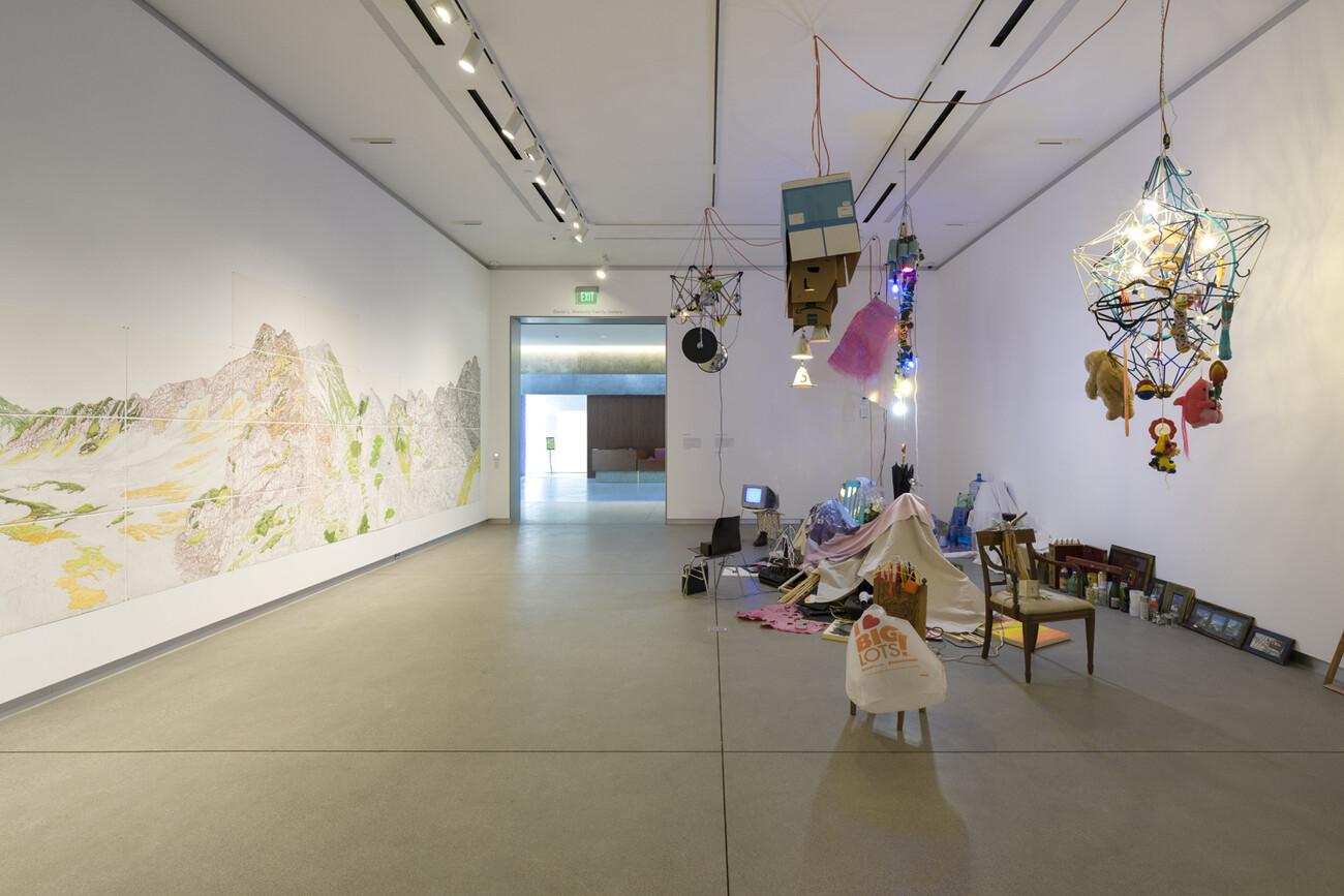 image of gallery with drawing on wall and installation of various objects