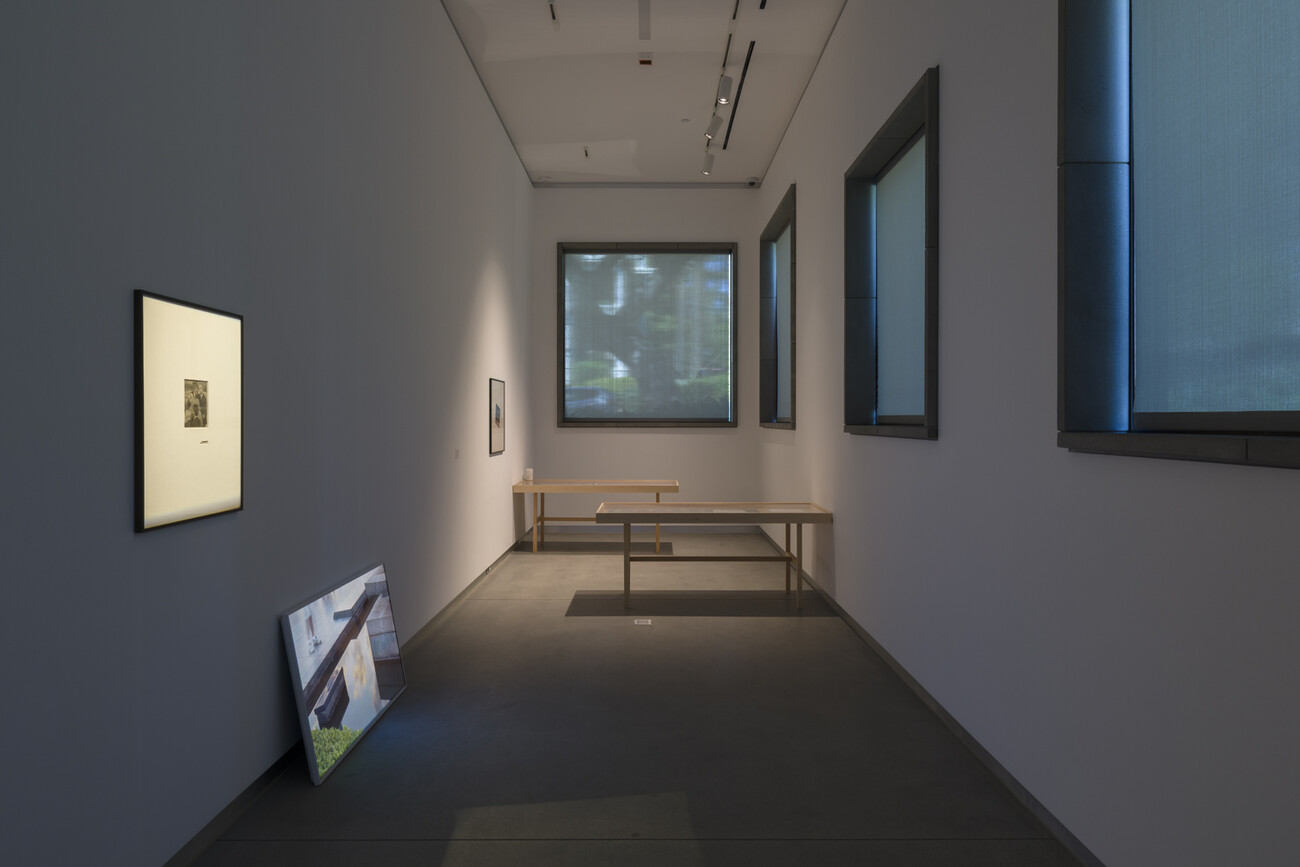 room with two tables, tv screen, and framed artworks