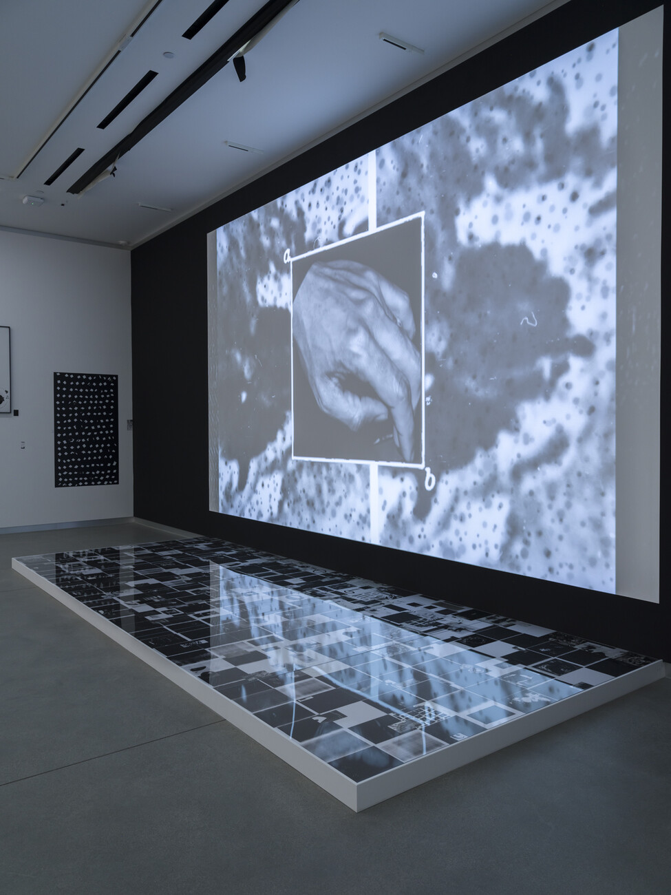 video on black wall with reflective platform underneath