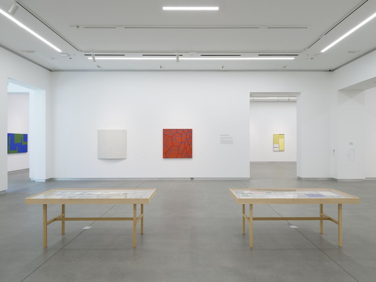 gallery with two wood tables and paintings on the walls