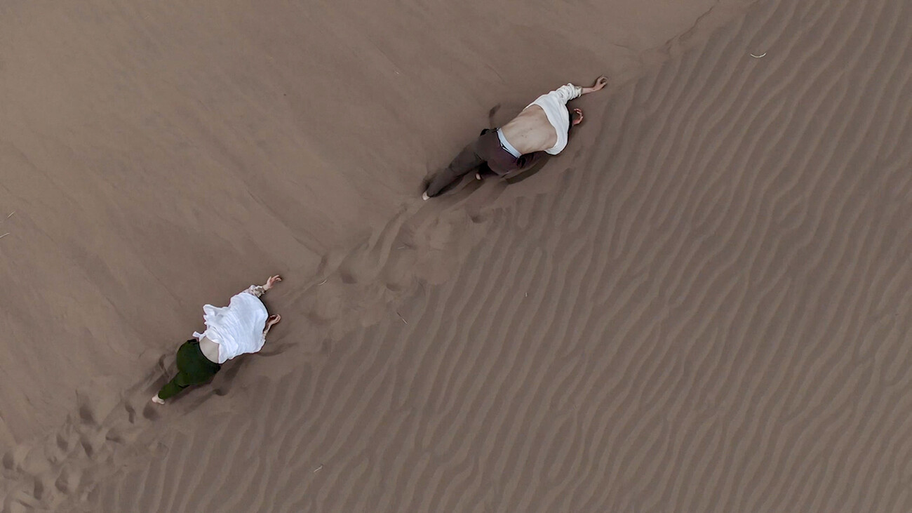 two people crawl on sand