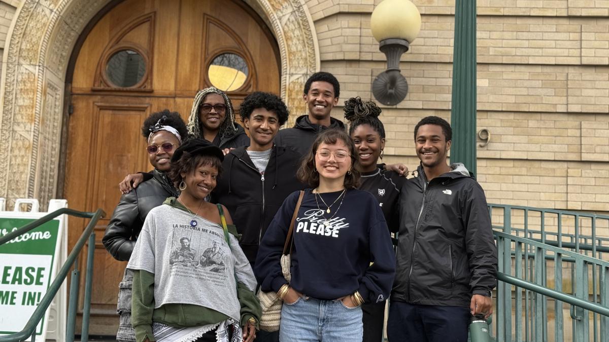 Students take a picture on the steps of a building.