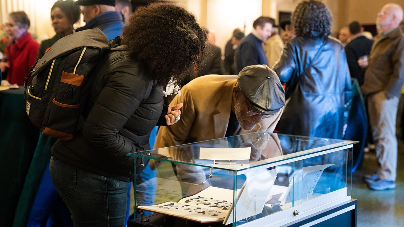 People looking at items in display case in lobby of Bridges Auditorium.