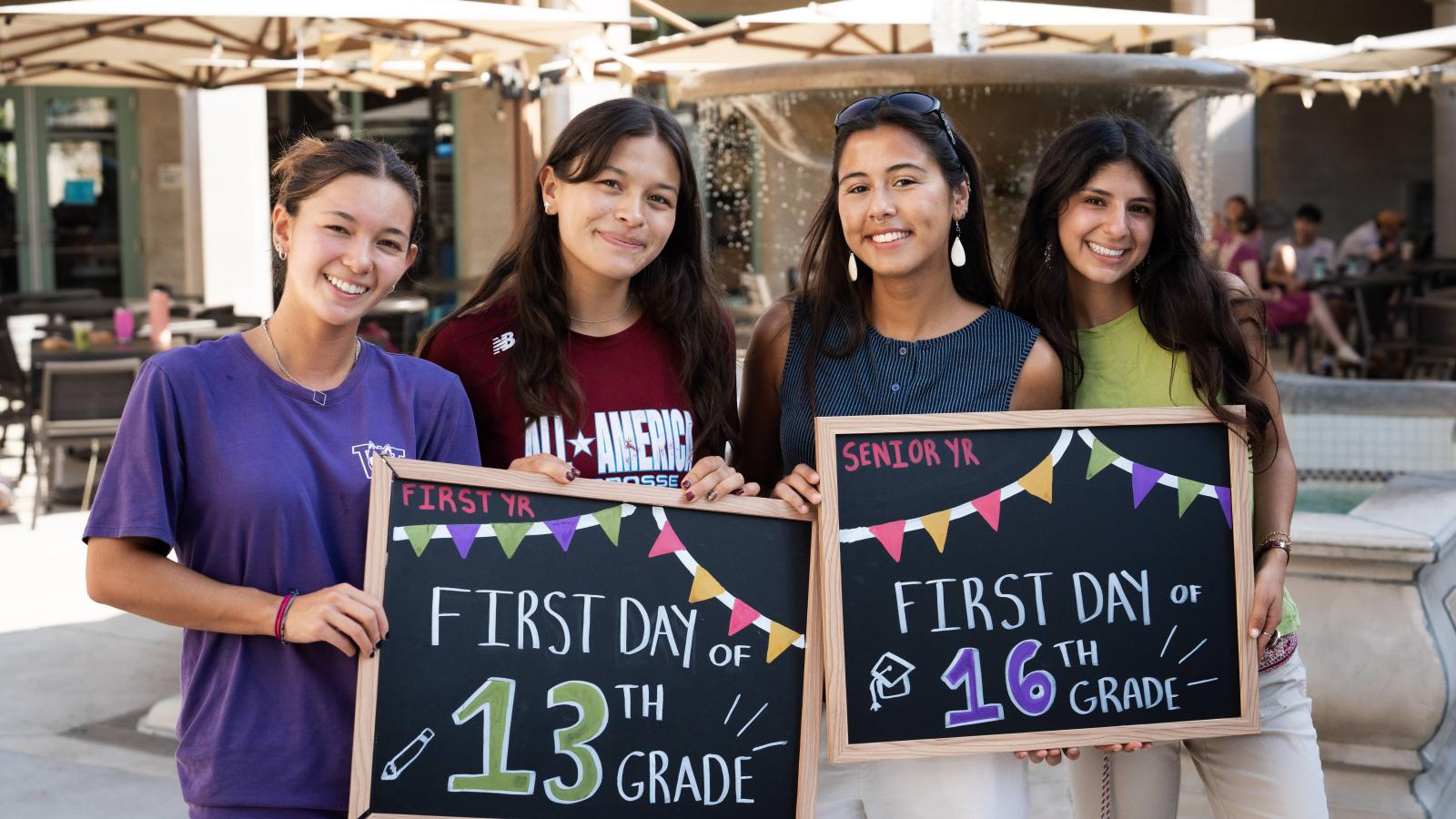 Four students hold chalkboards