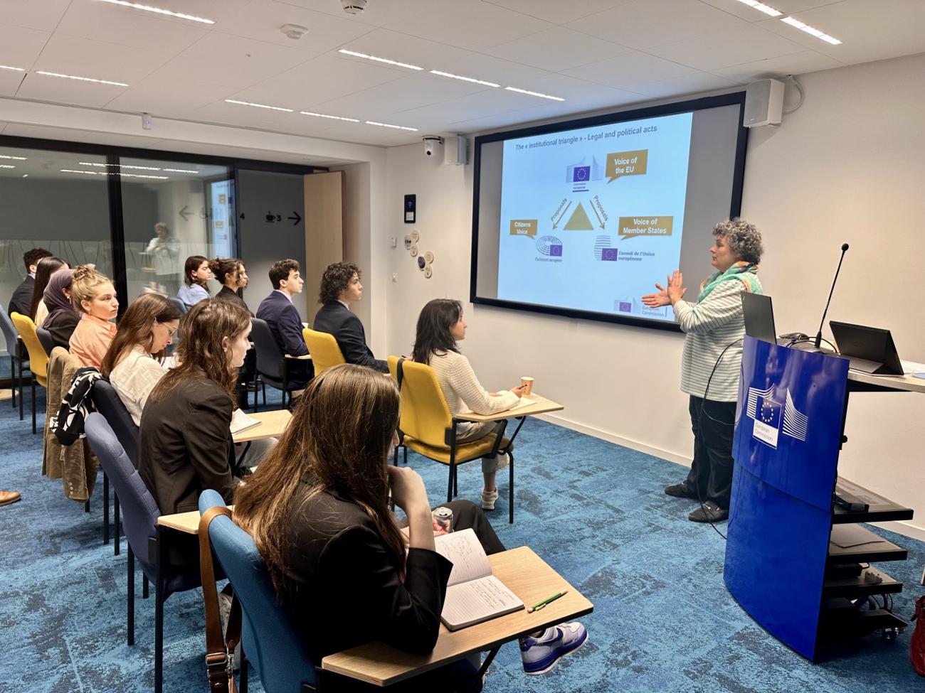 Classroom with students, speaker, and PowerPoint slide