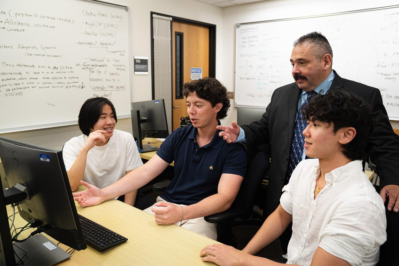 Prof. Roberto Garza-Lopez and SURP students with computer in classroom