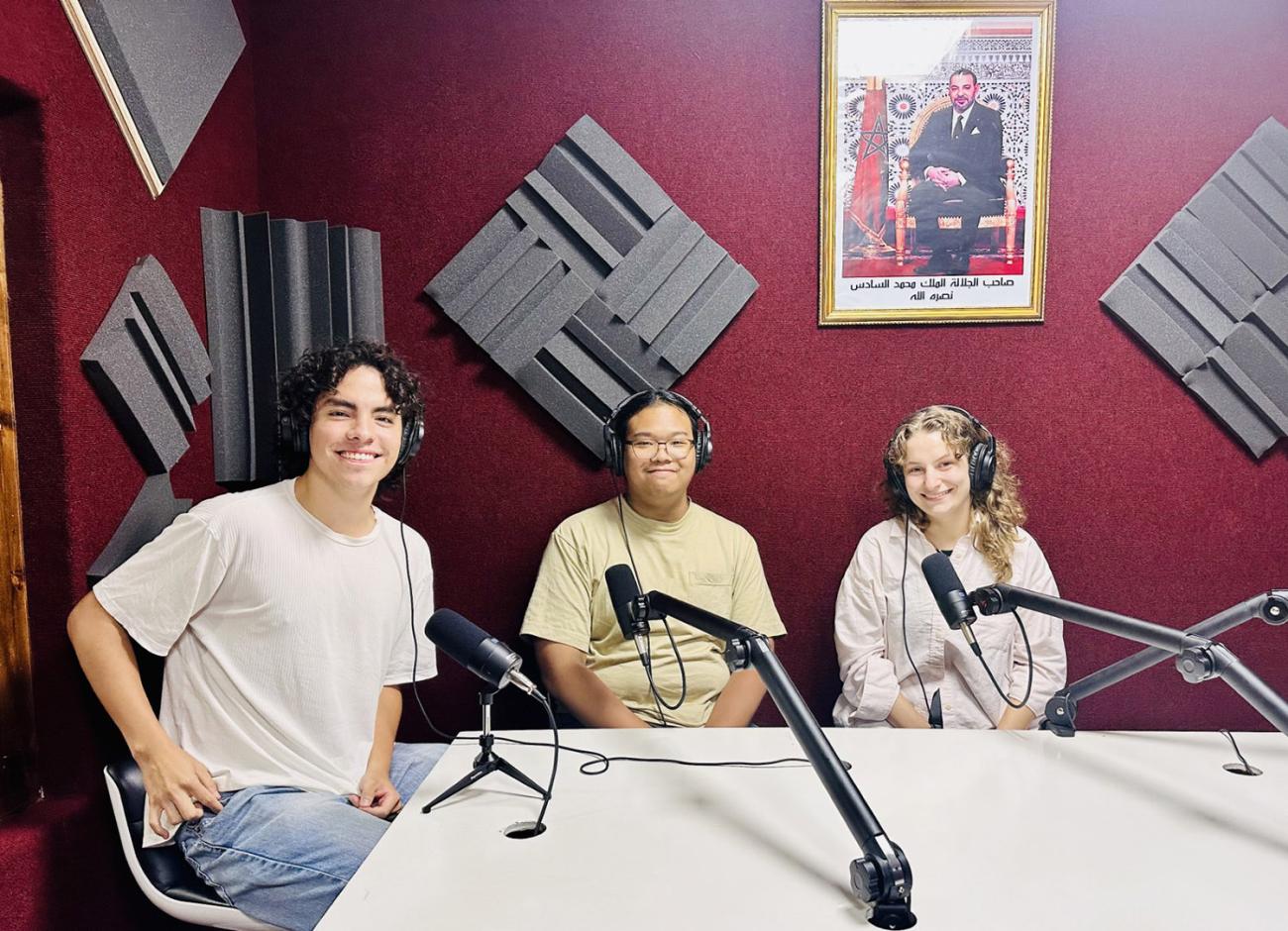 Three students wearing headphones in recording studio.