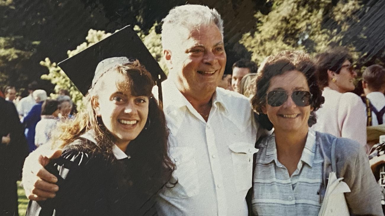 photo of Andrea Venezia in a cap and gown at Pomona College Commencement with her parents