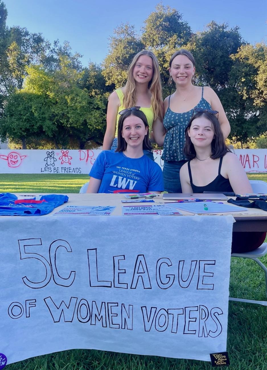 Four students stand behind a table
