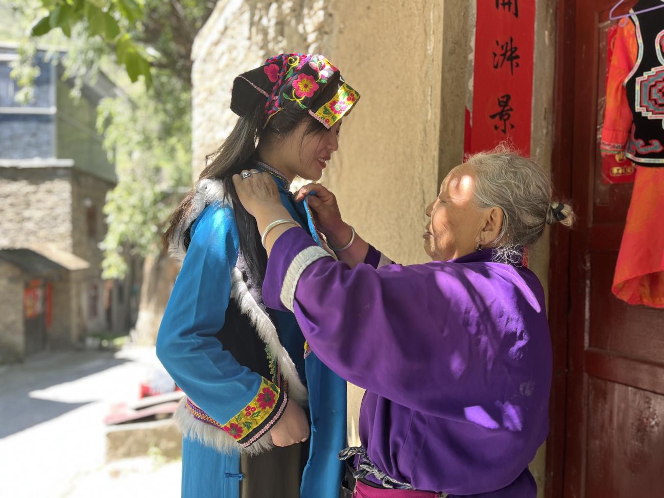 A woman adjusts another woman's clothes