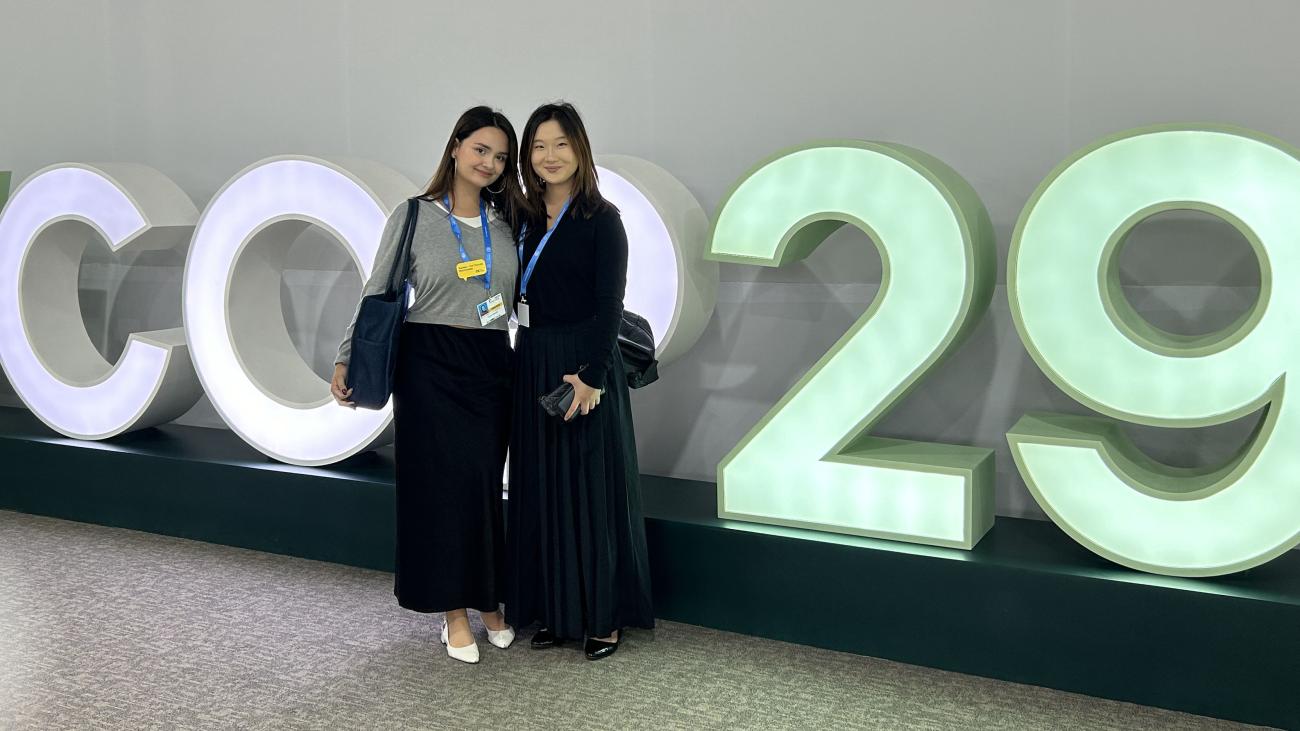 Laura Jaramillo and Gina Yum at COP29 in front of sign
