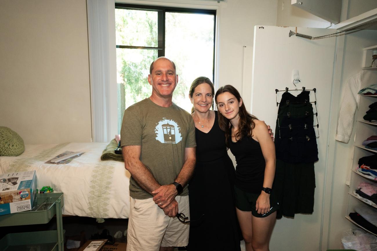 Student and parents pose for photo in dorm room