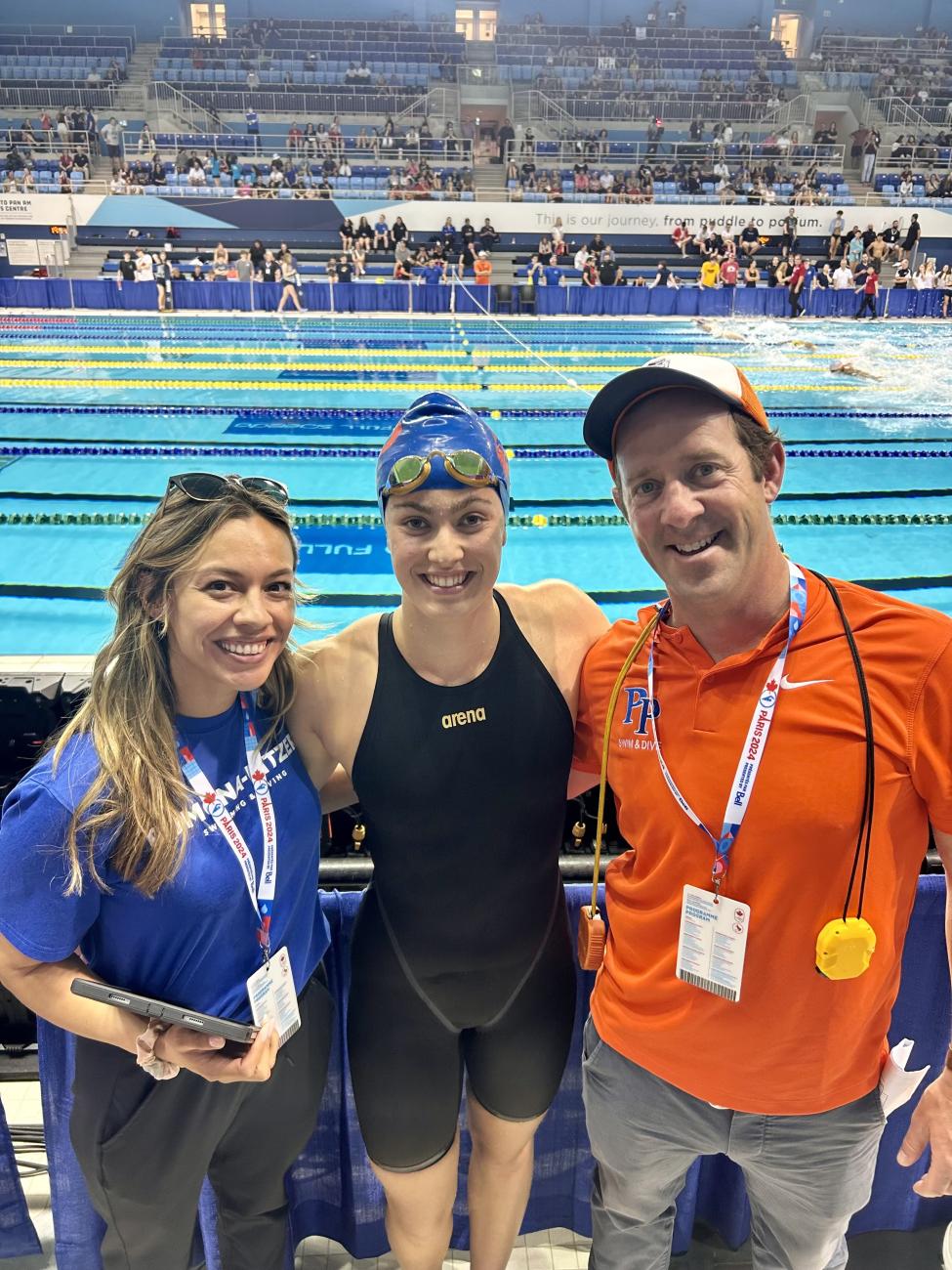 Three people pose for a photo in front of a pool.
