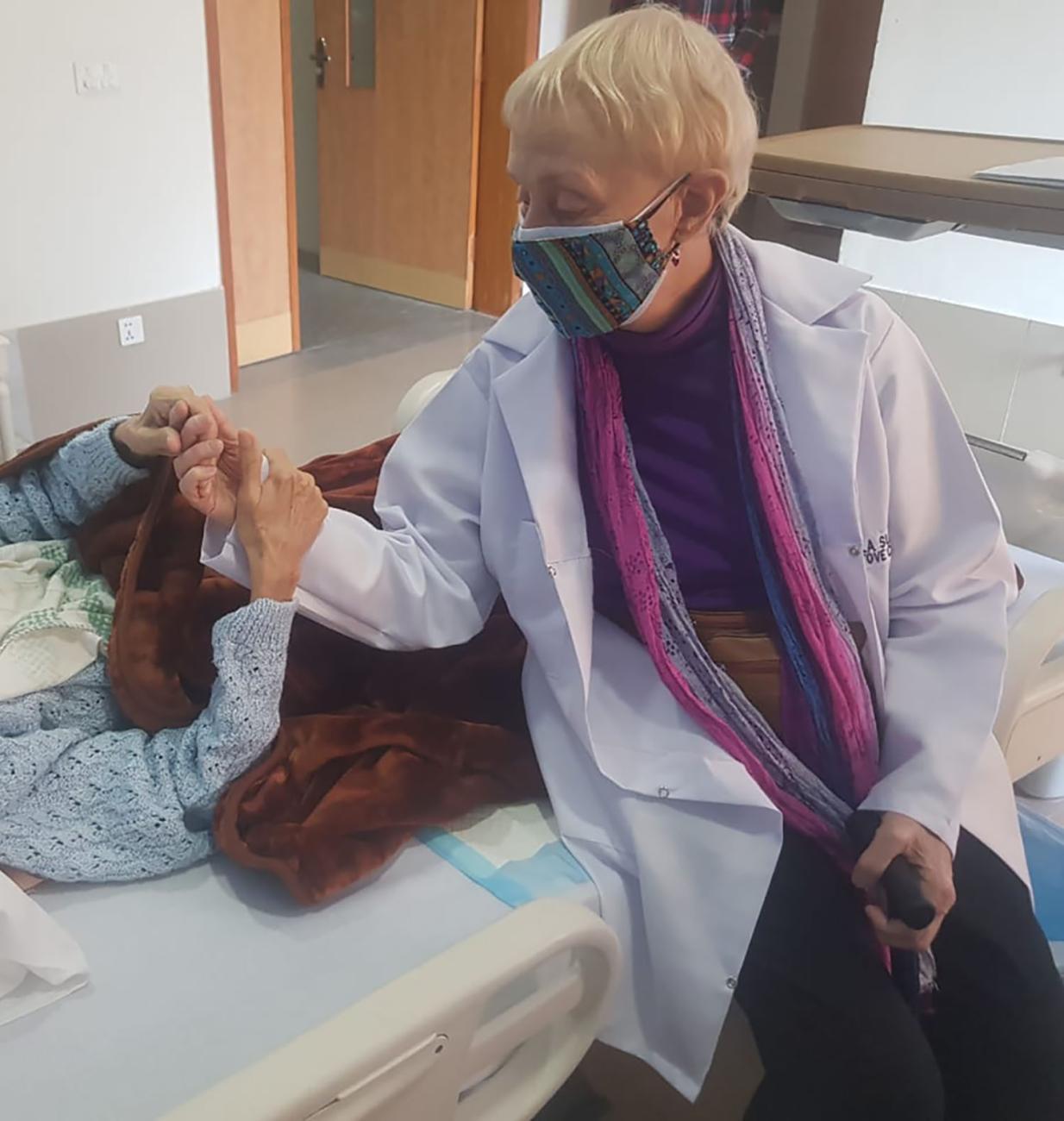 Pam Sutton holding the hands of her patient