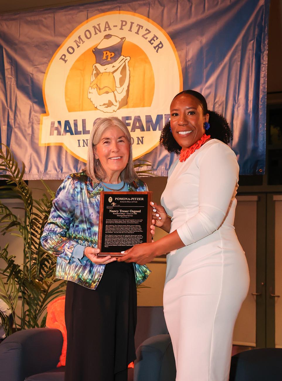 A photo of Athletics Director Miriam Merrill handing an award plaque to Nancy Treser-Osgood, Class of 1980, for her service to the Athletics Hall of Fame Committee.