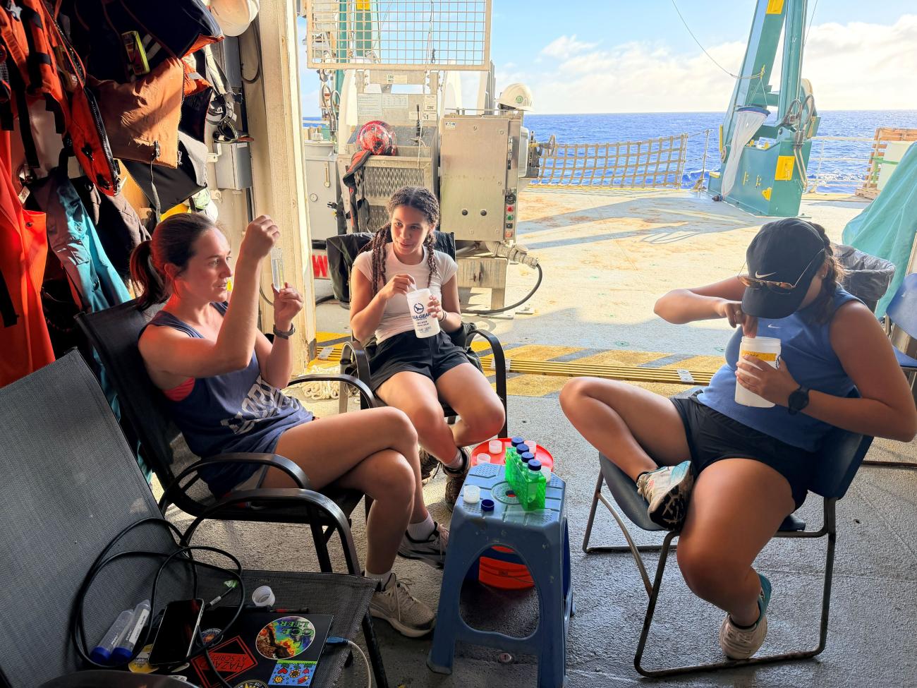 Students sit working on deck of boat