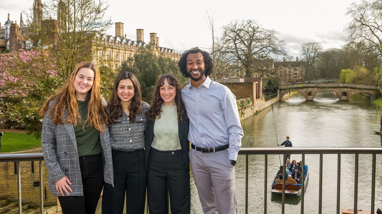 Four Pomona College alumni standing on a bridge over the River Cam in Cambridge, England