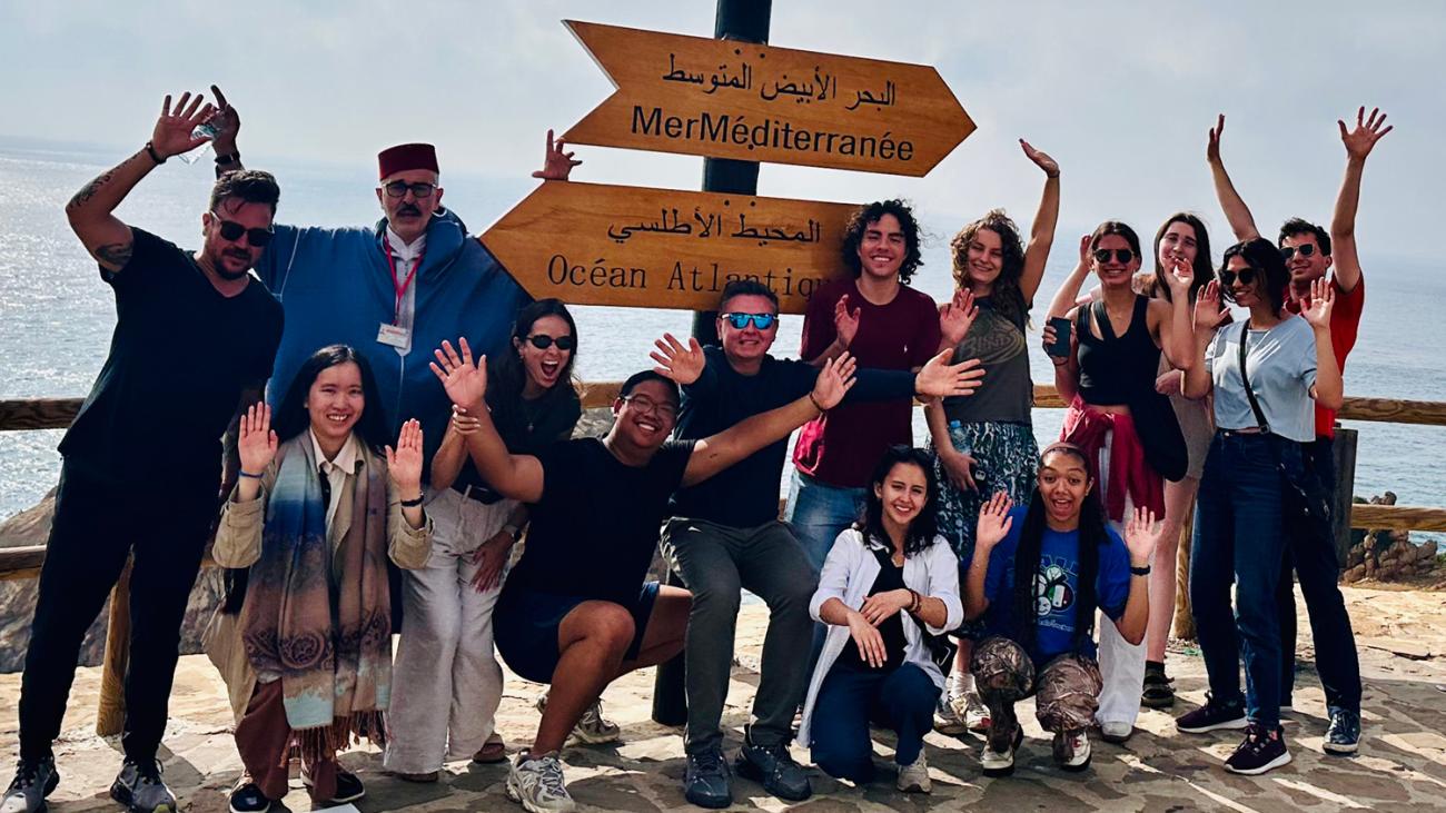 students and others in front of the ocean in Assilah