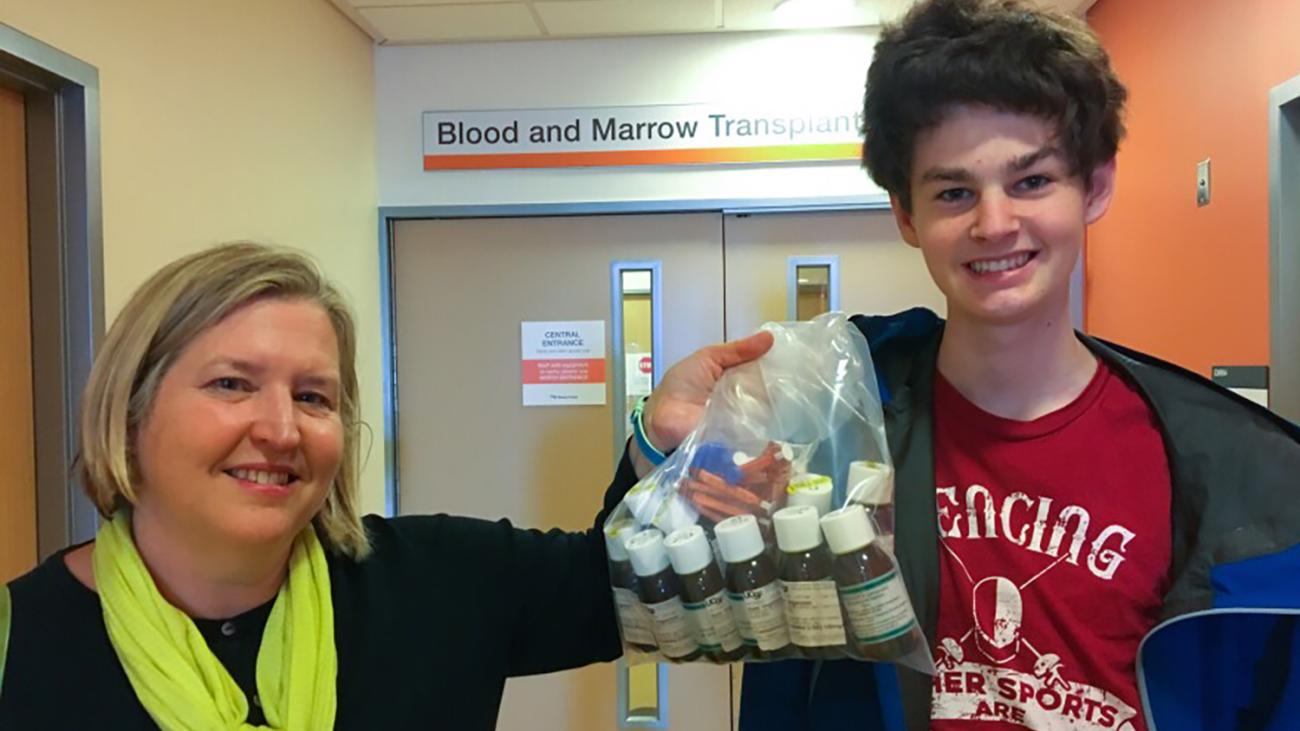 photo of alumni award winner evelyn nussenbaum holding a bag of medications posing with her son sam