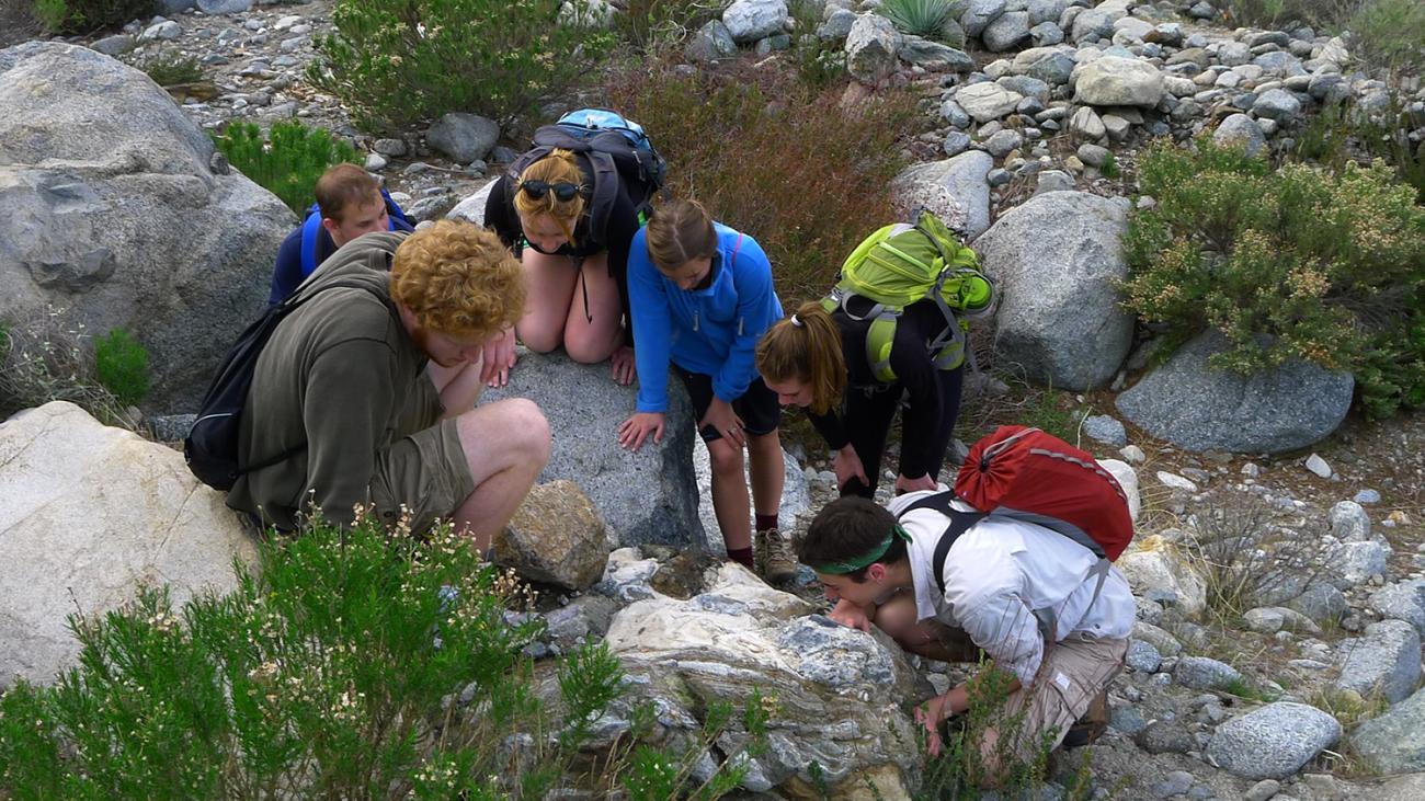 Pomona College geology students looking at rocks on a field trip
