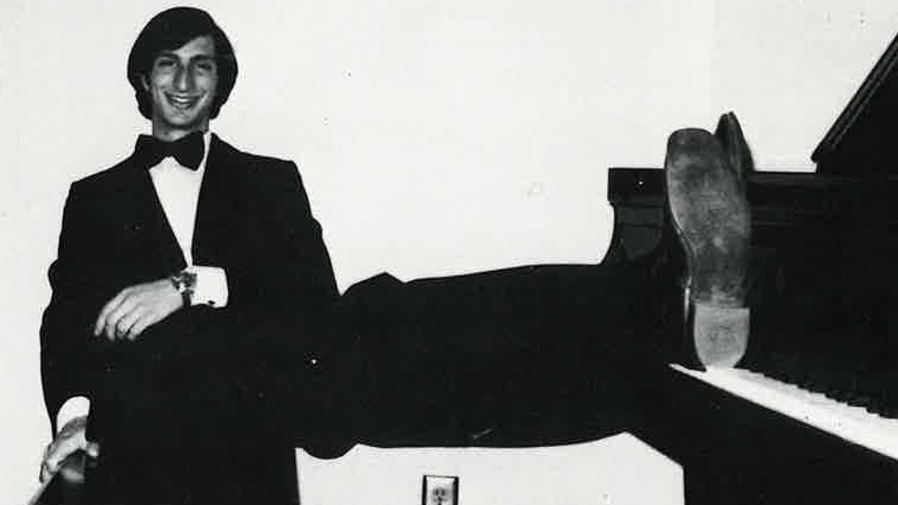 Alumnus Frank Albinder as a student at Pomona sits with his feet up on a piano.