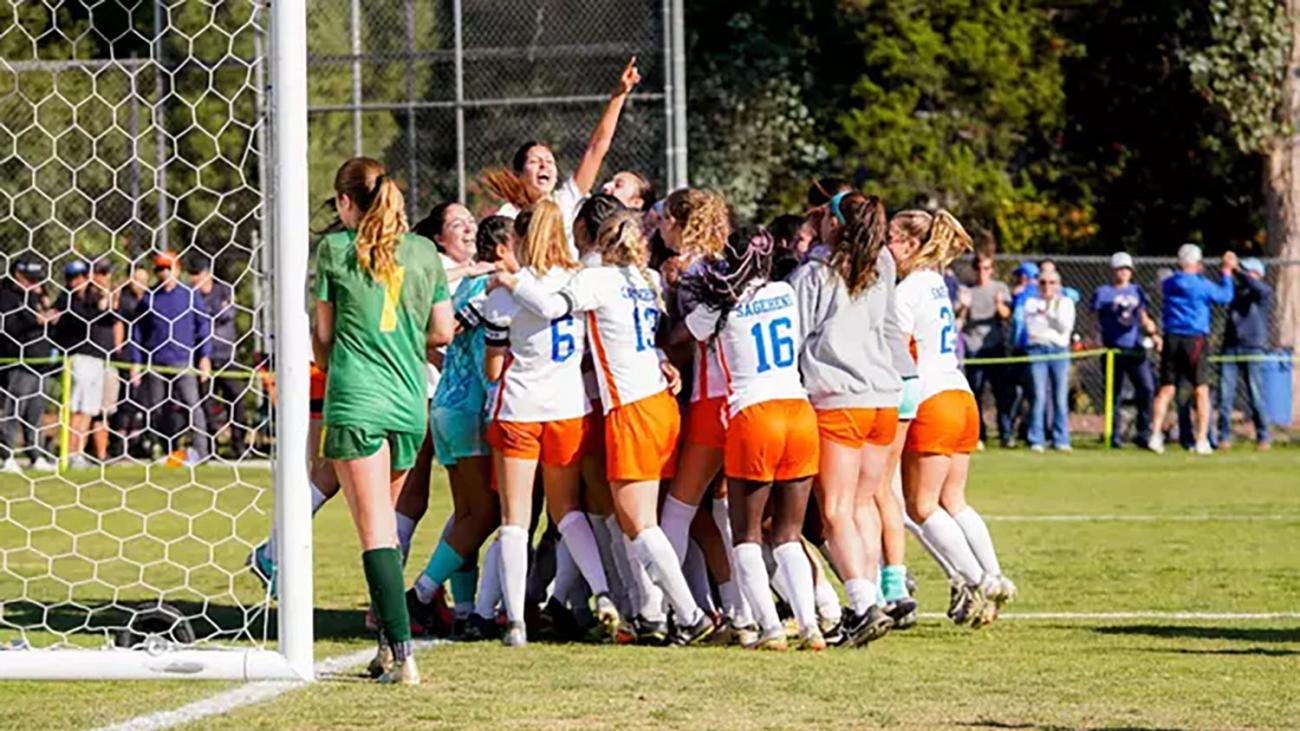 women's soccer team celebrate a win in a huddle